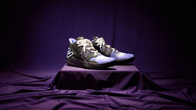 Side view of Coco Gauff's black and purple New Balance tennis shoes.